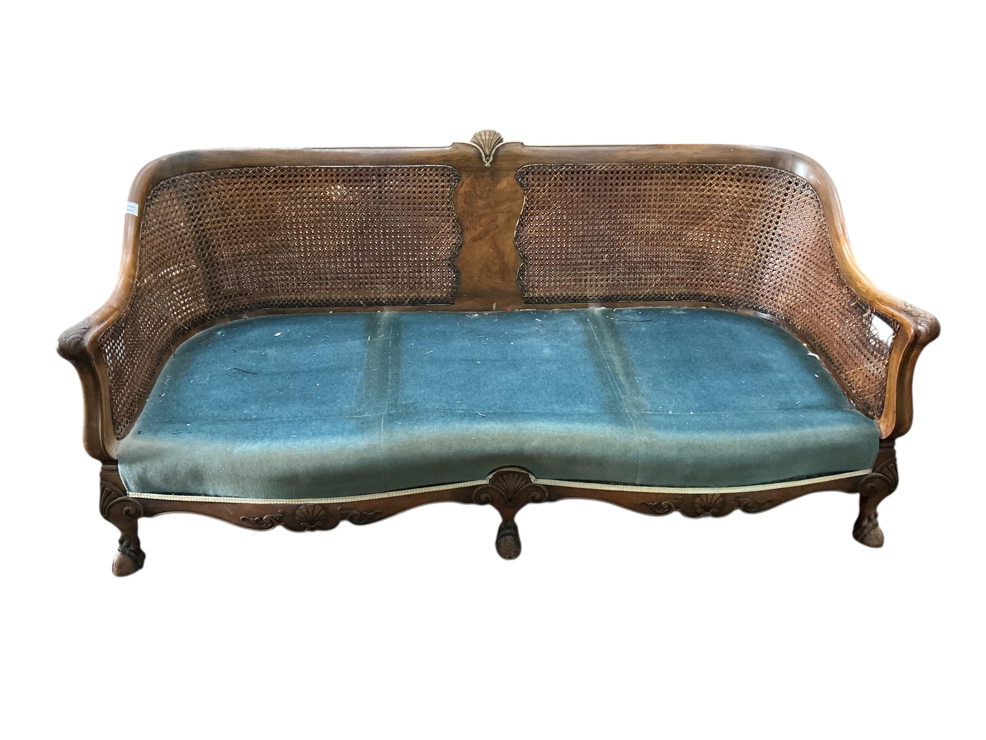 An early 20th century carved walnut and double canework three piece bergère suite, cane in need of repair